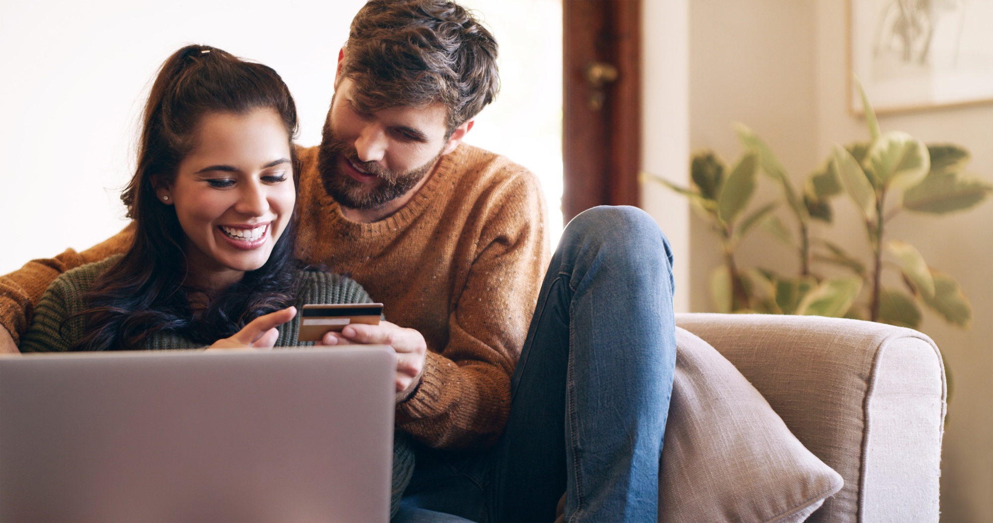Shot of a young couple using a laptop and credit card on the sofa at home