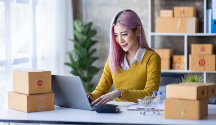 Startup SME small business entrepreneur of freelance Asian woman wearing apron using laptop and box